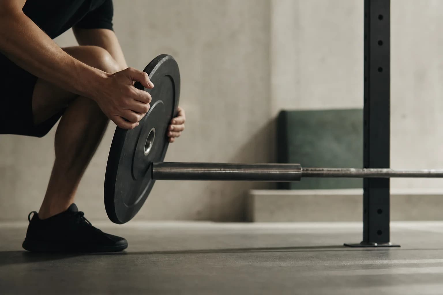 An athlete carefully loading a plate onto a barbell