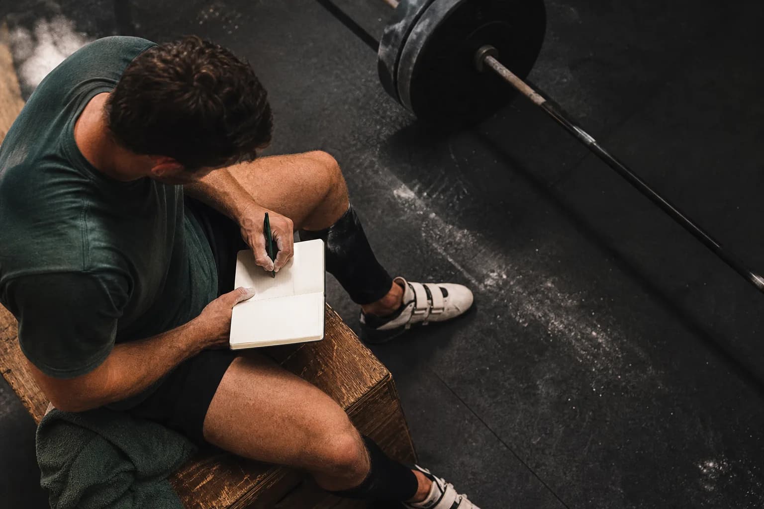 An athlete recording a completed lift in a paper training notebook